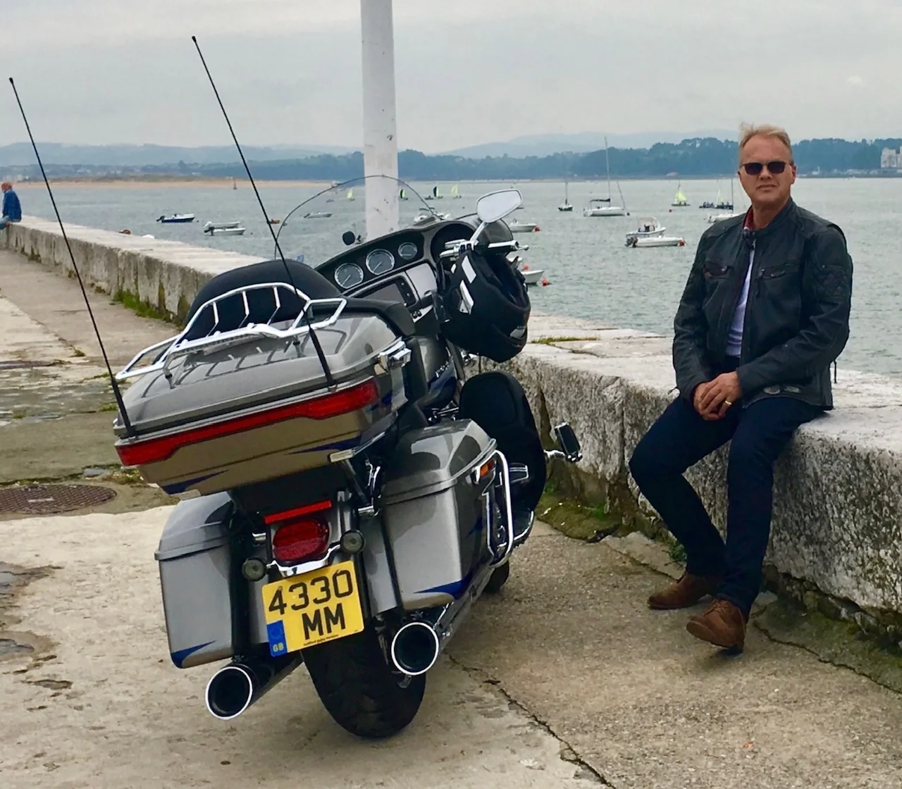 Marc sitting beside his Harley-Davidson motorcycle by the water