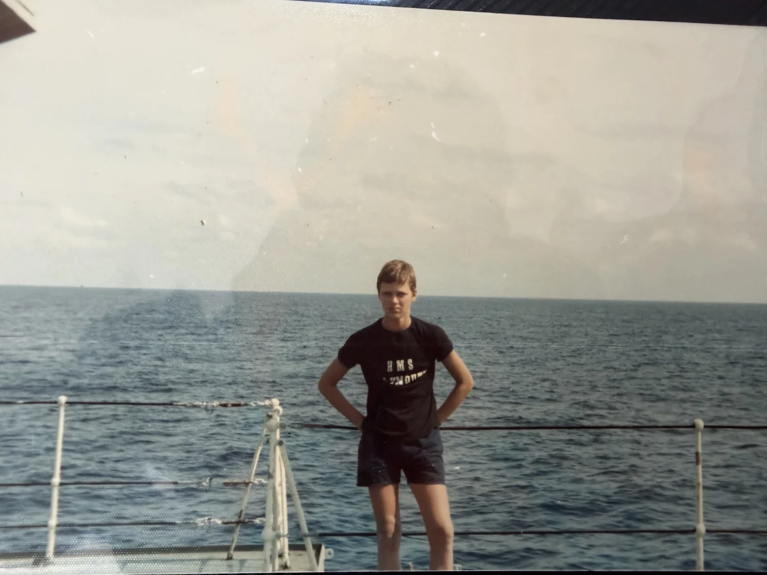 Young Marc standing on a ship with the sea behind him